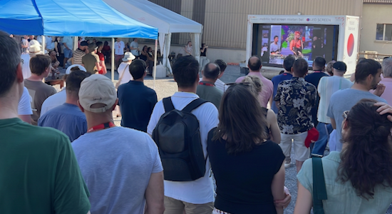 Mobiler LED-Screen Trailer mit integriertem Soundsystem für Events mieten Eine dichte Menschenmenge von hinten fotografiert blickt auf einen mobilen LED-Screen Trailer von LED-SCREEN, der im Außenbereich ein Video für die Eventbesucher abspielt.